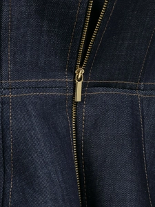 Macro detail of high-quality dark blue denim fabric with gold metal zipper and orange stitching