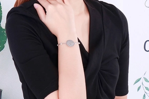 Detail of silver double-layer bracelet with floral medal pendant and white pearls