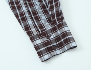Macro detail of plaid shirt cuff showing brown buttons and fine cotton fabric texture