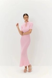 Dettaglio dell'abito in maglia rosa con scollo a goccia unico e trama a costine