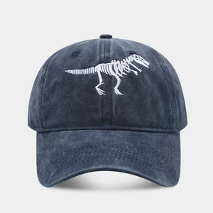 Close-up of white dinosaur skeleton embroidery on a navy washed cotton baseball cap