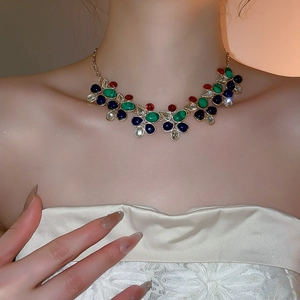 Detail shot of colorful teardrop and oval gemstone necklace set in golden finish on neck