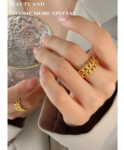 Close-up of golden double-layer Cuban link chain rings on a female model finger