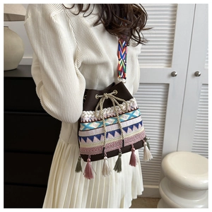 Detailed view of woven bucket bag featuring tassel drawstring and colorful ethnic strap