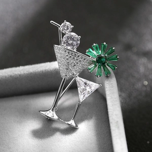 Detailed view of silver cocktail glass brooch with green gemstones and sparkling zircons