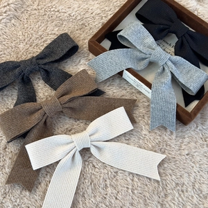 Knitted bow hair clip set in neutral colors on a soft plush and velvet background