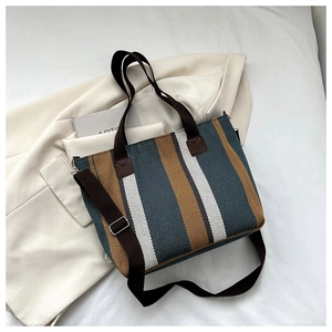Close-up of striped canvas tote bag on a beige blazer, highlighting texture and straps