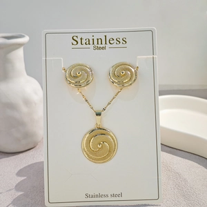 Macro detail of gold stainless steel swirl jewelry set on a white display card