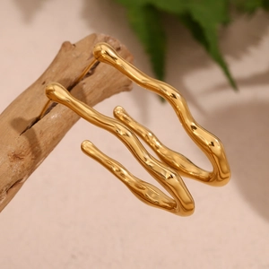 Detail of wave shaped 18K gold plated stainless steel hoop earrings with natural decor