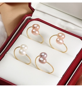 Detailed macro view of four freshwater pearl rings with twisted gold bands in a gift box