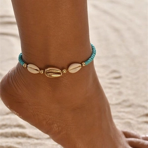 Bohemian anklet with turquoise beads and gold shell charms on a sandy beach background