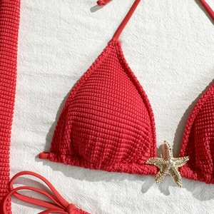 Close-up of red bikini top with textured fabric and sparkling rhinestone starfish accessory