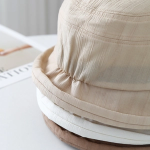 Detailed view of stacked ribbed bucket hats in beige, white, and brown fabrics