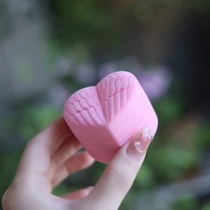 Macro shot of pink heart-shaped velvet jewelry box featuring embossed wing detail