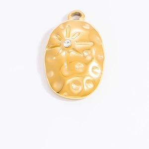 Macro view of gold stainless steel hammered oval pendant with sun star and crystal