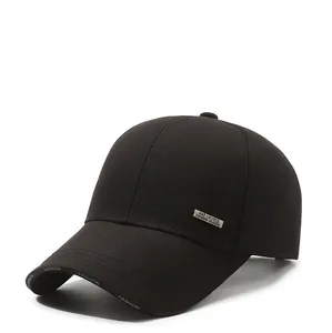 Detail of metal logo plaque and embroidered fashion text on black baseball cap
