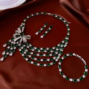 Luxury emerald zircon bow necklace and teardrop earrings set on red satin fabric