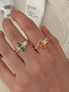 Close-up of irregular silver rings featuring marquise-cut green and orange gemstones