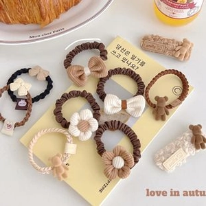 Macro detail of plush teddy bear and corduroy bow hair accessories in earthy tones