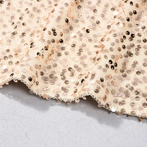 Vue macro de paillettes dorées haute densité sur tissu résille pour une robe ajustée