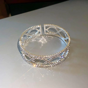 Macro-opname van zilveren crossover armband met dichte pavé diamantzetting en geometrisch design