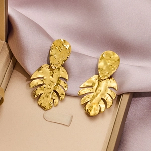 Golden monstera leaf earrings with hammered metal texture in a luxury gift box