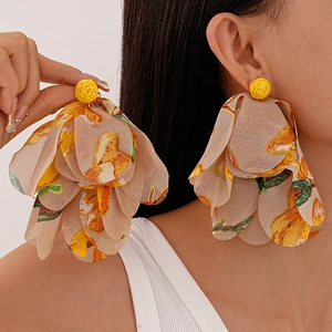 Macro view of woven raffia flower earrings with colorful fabric petals for a summer vacation look