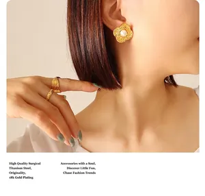 Macro detail of 18K gold plated surgical titanium flower earring with pearl on ear