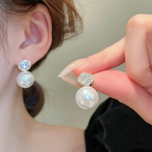 Detail of elegant pearl earrings with sparkling zircon stones and gold plating