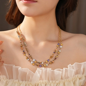 Detail of a double-layered gold necklace with colorful gemstones on a female model