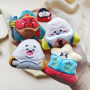 Main tenant des épingles en peluche brodées de figures traditionnelles chinoises