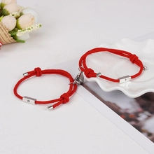 Dettaglio di braccialetti di coppia intrecciati rossi con chiusura magnetica a cuore