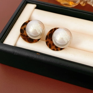 Detailed close-up of plush leopard print earrings with large lustrous white pearls