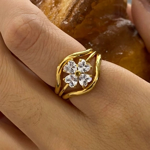 Close-up of golden clover ring with heart-shaped crystals on a waved double-line band