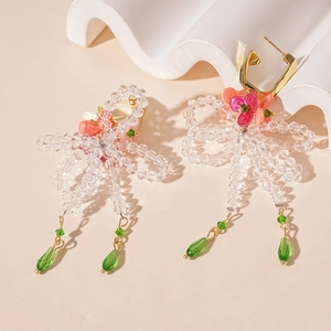 Detail of beaded earrings featuring bow design with pink floral accents and green drops