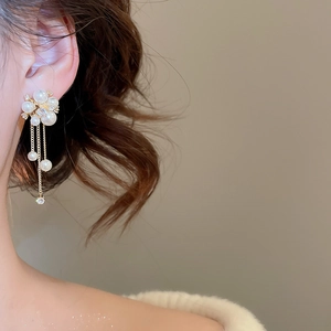 Detail of elegant gold flower earrings with pearls and tassels on model profile