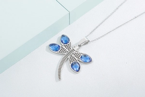 Close-up of silver dragonfly necklace with blue crystal wings and mesh body detail