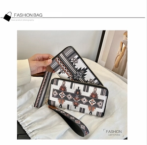 Detailed view of women's long zip wallet with tribal geometric patterns and wrist strap