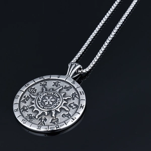 Macro shot of vintage silver-tone medallion pendant featuring zodiac sun and floral engraving