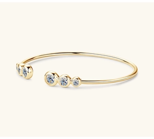 Dettaglio di un bracciale aperto dorato con pietre preziose scintillanti in sfumatura