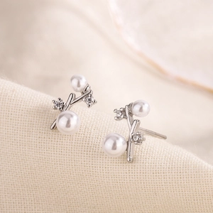 Elegant branch shaped silver stud earrings with pearls and zircon stones on beige fabric