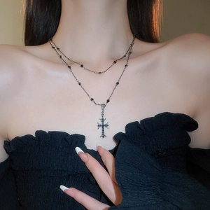 Detail of a punk double-layer cross necklace with black beads on a female model neck