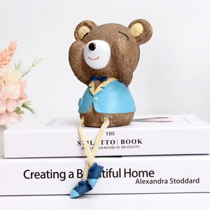 Detail of cute resin bear figurine in blue suit sitting on books for home decoration