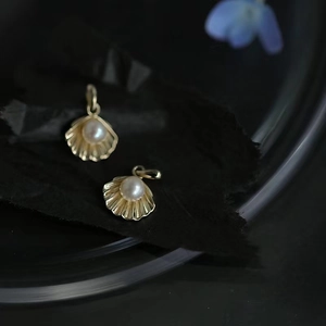 Macro shot of 14k gold shell pendant with white pearl inlay on dark textured background