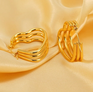 Détail de boucles d'oreilles créoles cœur en or 18 carats sur satin jaune élégant