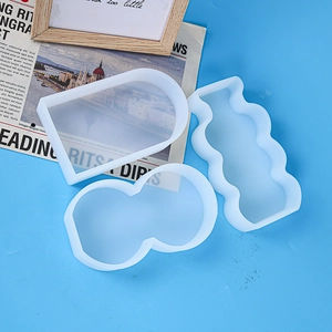 Three geometric silicone molds for candles including arch wave and peanut shapes on blue background