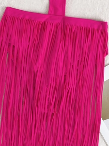 Détail d'une jupe de bikini rose vif à longues franges sur un fond de fausse fourrure