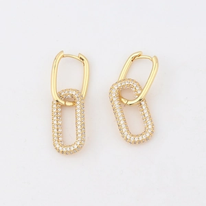 Detailed close-up of golden oval hoop earrings with sparkling micro-pave crystals