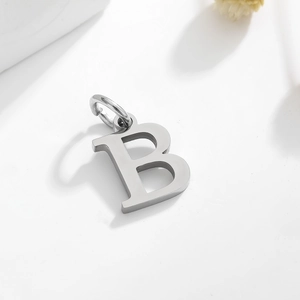 Macro shot of a silver letter B pendant with a top ring on a white studio background