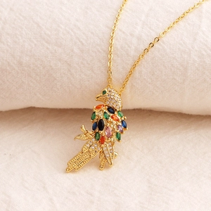 Goldene Vogel-Anhänger Halskette mit bunten Zirkoniasteinen auf weißem Stoffhintergrund
